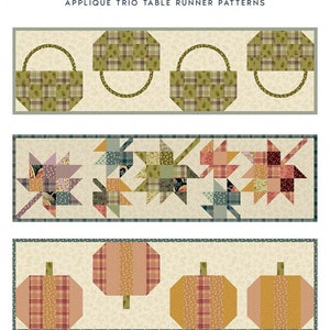 May include: A quilt pattern titled "Fall Trio" featuring three table runner designs. The designs include baskets, leaves, and pumpkins, all in autumnal colors. The table runner sizes are 12.5 inches by 45 inches.