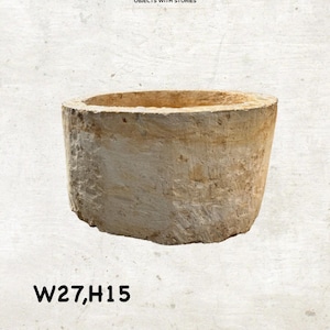 May include: A cylindrical, beige-colored planter with a rough, textured surface. The planter has a wide opening and is approximately 10.6 inches wide and 5.9 inches high. The text "CURATED STUDIO" and "OBJECTS WITH STORIES" are at the top.