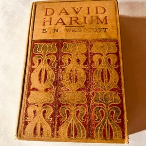 May include: A vintage book titled "David Harum" by E.N. Westcott. The cover is brown with gold and red decorative patterns.