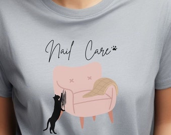 May include: A gray t-shirt with a black cat scratching a pink armchair. The text "Nail Care" is written in cursive above the armchair.