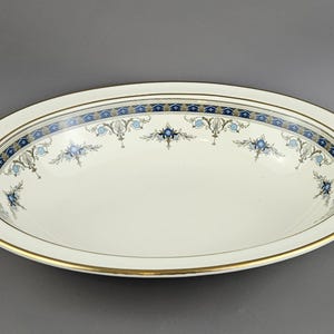 Puede incluir: Plato ovalado para servir con interior color crema y borde decorativo. El borde presenta un diseño floral azul y dorado. El borde está adornado con una banda dorada. Una pieza clásica para servir alimentos.