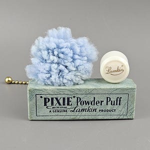May include: A vintage "Pixie" powder puff set. The set includes a light blue powder puff, a small white jar with the "Lamkin" logo, and a box with the text "Pixie Powder Puff" and "A Genuine Lamkin Product".