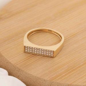 May include: A gold ring with a rectangular band set with small diamonds.