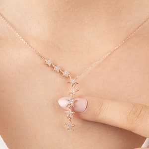 May include: A rose gold necklace with a delicate chain and a pendant featuring a cascade of small, sparkling stars.
