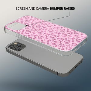 May include: A clear phone case with a pink Hello Kitty pattern is shown on top of a silver phone. The case has a raised screen and camera bumper. The Hello Kitty design is repeated across the case.