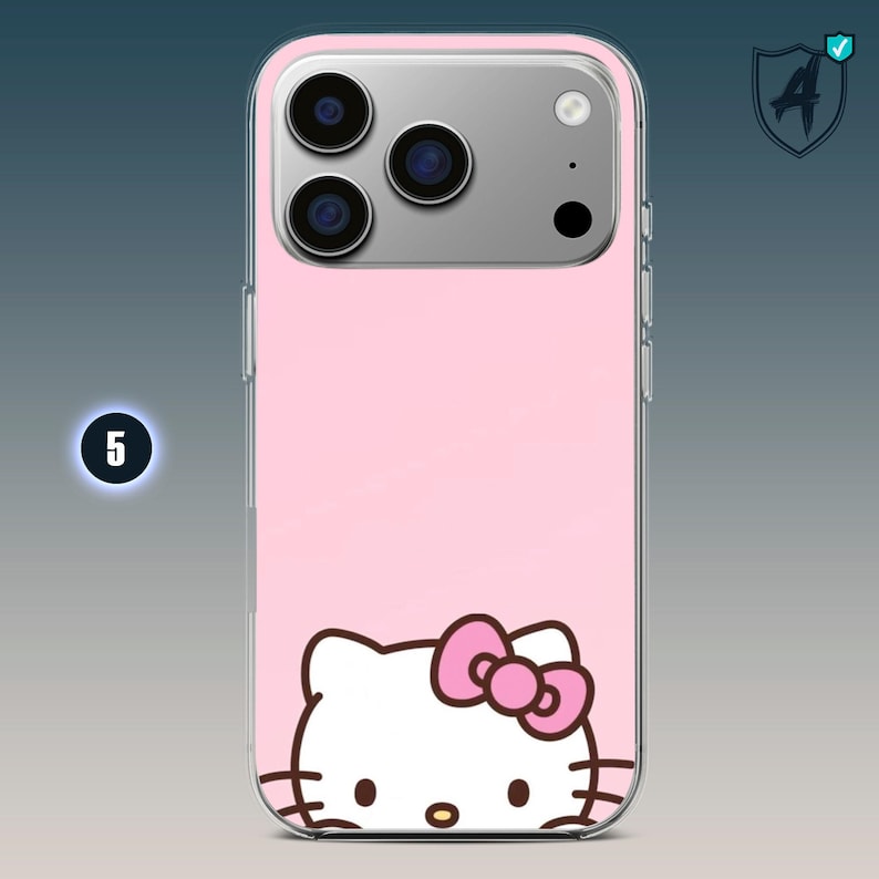 May include: Pink phone case featuring a Hello Kitty design. The case has a clear border and a pink background. The Hello Kitty graphic includes a pink bow and is positioned at the bottom of the case. The phone's camera lenses are visible at the top.