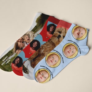 May include: Four pairs of socks with different designs. One pair is red with a heart design and a photo of a woman. Another pair is blue with a photo of a baby and the text "Happy Birthday, Dylan!" One pair is white with a photo of a dog and a woman. The last pair is blue with a photo of a family and the text "Happy Mother's Day, Mom!"