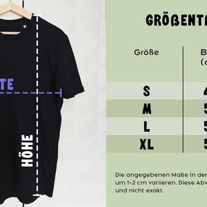 May include: Black t-shirt hanging on a wooden hanger. The image includes a size chart with measurements in centimeters: S (48 cm width, 67 cm height), M (53 cm width, 72 cm height), L (56 cm width, 74 cm height), and XL (59 cm width, 76 cm height).