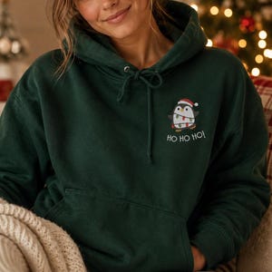 Frau trägt einen bestickten Pinguin Weihnachtspullover in gemütlicher Weihnachtsatmosphäre.