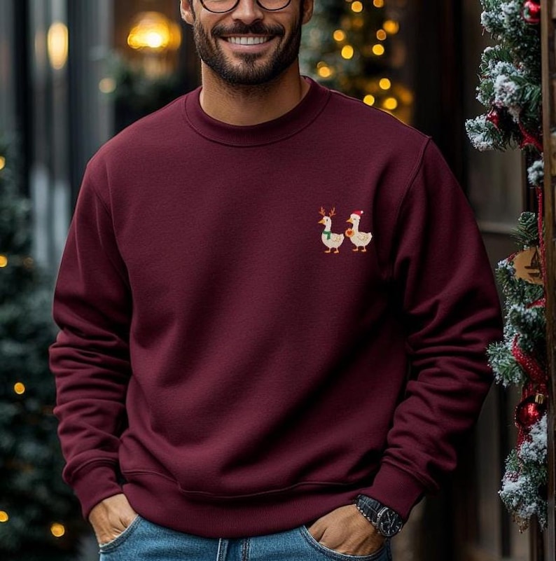 Mann trägt lustigen Weihnachtspullover mit bestickter Ente oder Gans in gemütlicher Weihnachtsatmosphäre.