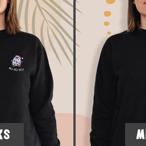 May include: A black long-sleeve sweatshirt featuring a small embroidered graphic on the left chest of a penguin wearing a Santa hat and scarf, with the text "HO HO HO!" embroidered in white thread underneath the penguin figure.