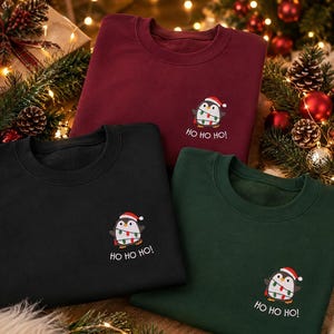 Bestickter Weihnachtspullover mit kleinem Pinguin Weihnachtsmotiv für Damen und Herren.