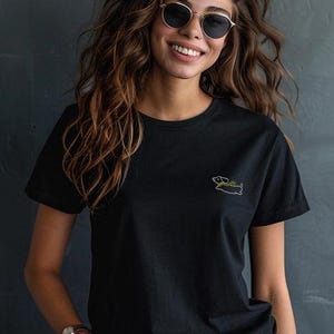 May include: A black t-shirt with a small embroidered image of a dachshund wearing a green hat.
