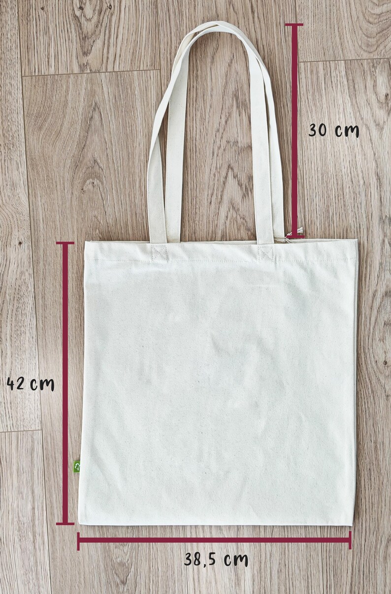 Puede incluir: Una bolsa de tela de lona blanca con dos asas. La bolsa mide 38,5 cm de ancho, 30 cm de alto y 42 cm de largo.