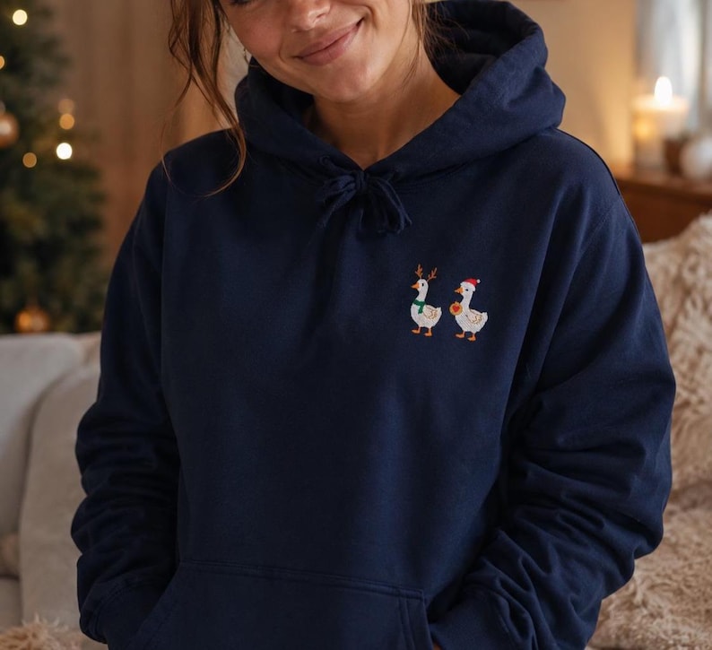 Frau trägt bestickten Weihnachts Hoodie mit süßer Ente vor weihnachtlichem Hintergrund, Geschenkidee für Tierliebhaber.