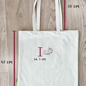 Puede incluir: Una bolsa de tela blanca con un gr&aacute;fico de una nutria y el texto "I my Otter Half". La bolsa mide 42 cm de alto, 38,5 cm de ancho y tiene asas de 30 cm. El gr&aacute;fico mide aproximadamente 5 cm.
