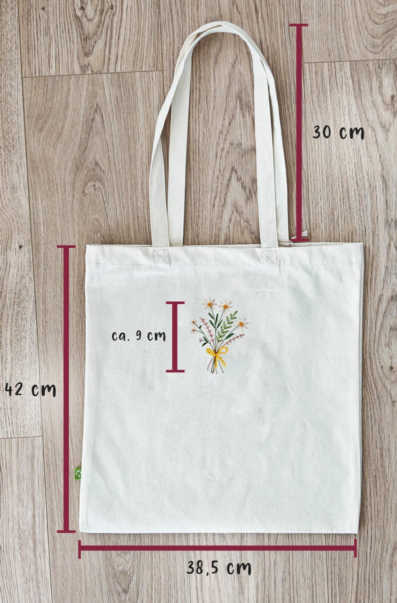 May include: A white canvas tote bag with a floral design and the letter "I" in red. The bag measures 38.5 inches wide, 42 inches tall, and 30 inches in height.