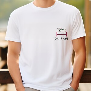 May include: White t-shirt with a small graphic of a dog jumping over a hurdle. The text "ca. 5 cm" is printed below the graphic.