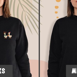 May include: Black sweatshirt with a small embroidered design of two geese, one wearing a Santa hat and the other wearing antlers. The word "LINKS" is printed on a black rectangle at the bottom of the image.