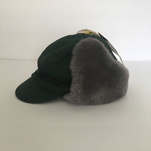 May include: A dark green winter hat with a faux fur ear flap and a bill. The hat has a yellow buckle on the top.