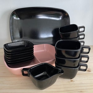 May include: A set of black plastic dishes, including a large rectangular serving platter, a divided serving dish with a pink center, and several small square bowls and cups.