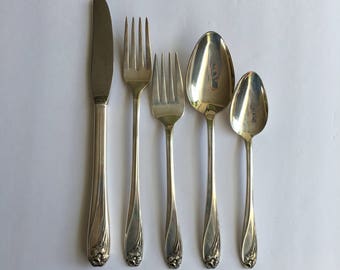 May include: Set of five silver-plated flatware pieces, including a knife, two forks, and two spoons. The handles are decorated with floral designs.