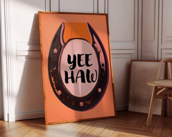May include: A peach-colored poster with a black horseshoe design. The horseshoe has a pink circle in the center with the text "YEE HAW" in black.
