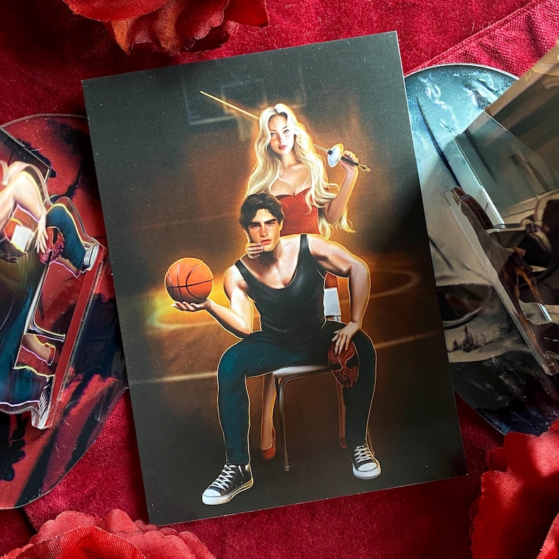 May include: A man and a woman in a basketball court setting. The man is sitting on a chair holding a basketball. The woman is standing behind him holding a sword. The man is wearing a black tank top and blue jeans. The woman is wearing a red top and white pants.