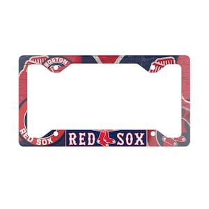 Puede incluir: Marco para matrícula de los Red Sox con un fondo de madera desgastado y el logotipo del equipo. El marco es rojo, blanco y azul con las palabras "Red Sox" en blanco.