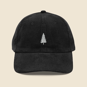 May include: Black corduroy baseball cap featuring a white embroidered pine tree design. The cap has a curved brim and an adjustable strap at the back. A classic, casual accessory for outdoor enthusiasts.