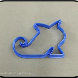 May include: Blue plastic cookie cutter shaped like a shoe with a curled toe.  The cookie cutter is on a gray surface.