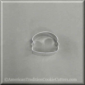 May include: A silver metal cookie cutter shaped like a hamburger. The cutter has a rounded top bun, a bottom bun, and a patty in between.