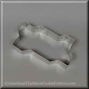May include: A silver metal cookie cutter shaped like a Christmas tree. The cutter has a wavy edge and a pointed top.