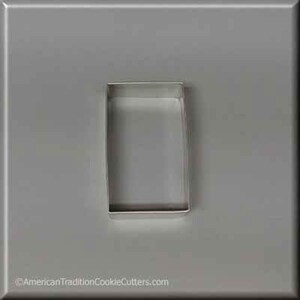 May include: A silver metal cookie cutter shaped like a rectangle. The cutter is on a gray background.