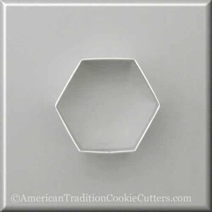May include: A silver-colored, hexagon-shaped cookie cutter. The cutter is made of metal and is set against a gray background. The text "AmericanTraditionCookieCutters.com" is at the bottom.