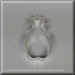 May include: A silver metal pineapple cookie cutter. The cutter is shaped like a pineapple with a star-shaped top.