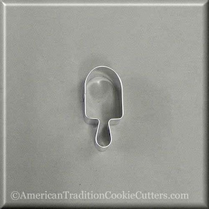 May include: A silver metal cookie cutter shaped like an ice cream popsicle on a gray background.