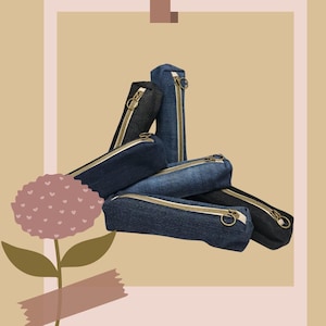 Peut inclure: Plusieurs trousses à crayons en jean de différentes nuances de bleu et de noir. Chaque trousse est dotée d'une fermeture éclair dorée et d'une forme rectangulaire. Les trousses sont empilées, certaines debout et d'autres à plat.