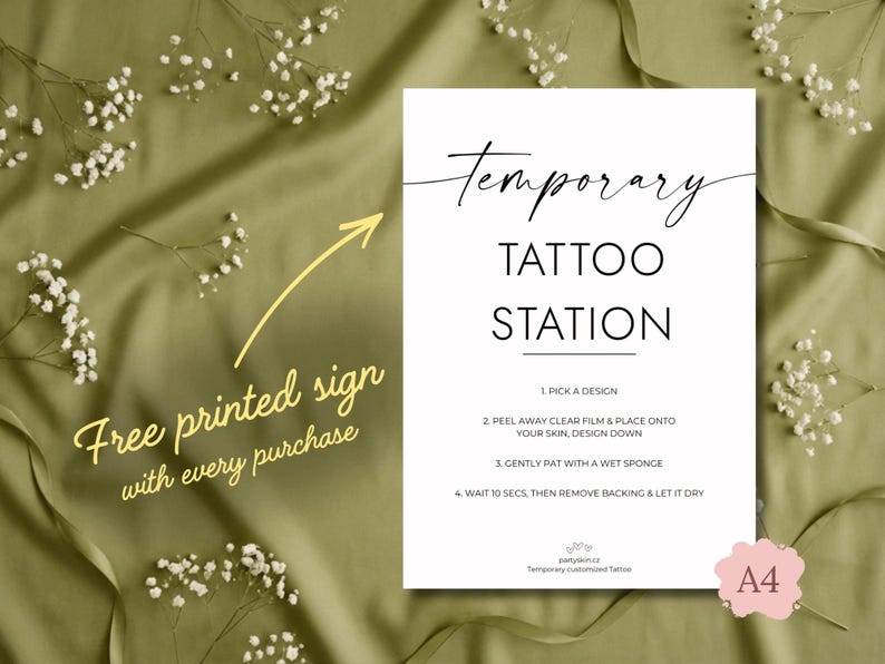 Pode incluir: Uma placa branca com a frase "Temporary Tattoo Station" em texto preto. As instru&ccedil;&otilde;es para aplicar tatuagens tempor&aacute;rias est&atilde;o listadas. Uma seta amarela aponta para o texto "Free printed sign with every purchase".