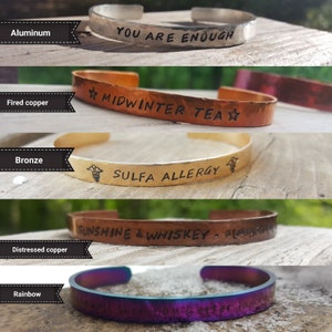 May include: Five different metal bracelets with various engraved messages. The bracelets are made of aluminum, fired copper, bronze, distressed copper, and rainbow.