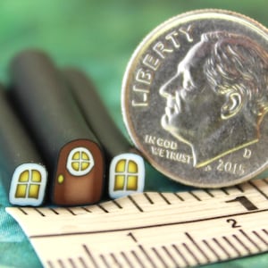 May include: Close-up of miniature polymer clay house canes with a brown door and yellow windows. A U.S. dime coin and a ruler are next to the canes. The coin shows the year 2015.
