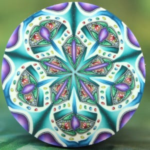 May include: A round, colorful decorative object with a symmetrical design. The object features a central starburst pattern in shades of purple, teal, and green, with accents of red and yellow. The design is intricate and detailed, with a mosaic-like appearance.