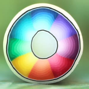 May include: A circular bead featuring a vibrant rainbow color gradient arranged in radial segments. The design transitions through shades of green, blue, purple, pink, red, and orange, separated by thin black lines, with a white center hole.