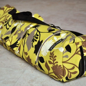 May include: A yellow yoga mat bag with a black strap and floral print. The bag has two zippered pockets and the text "Yoga Sweet" is printed on the front.