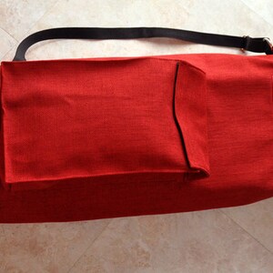 Pu&ograve; includere: Borsa per tappetino da yoga rossa con una tracolla nera e una tasca con cerniera. La borsa ha una piccola tasca sul davanti e il testo "Jenna & Co." stampato sul lato.