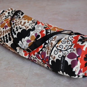 May include: A black and white floral patterned yoga mat bag with a black strap and a zipper closure. The bag has a label that says "Jenna & Trent".