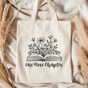 May include: A white canvas tote bag with black text and a graphic of an open book with flowers growing out of it. The text reads "One More Chapter".