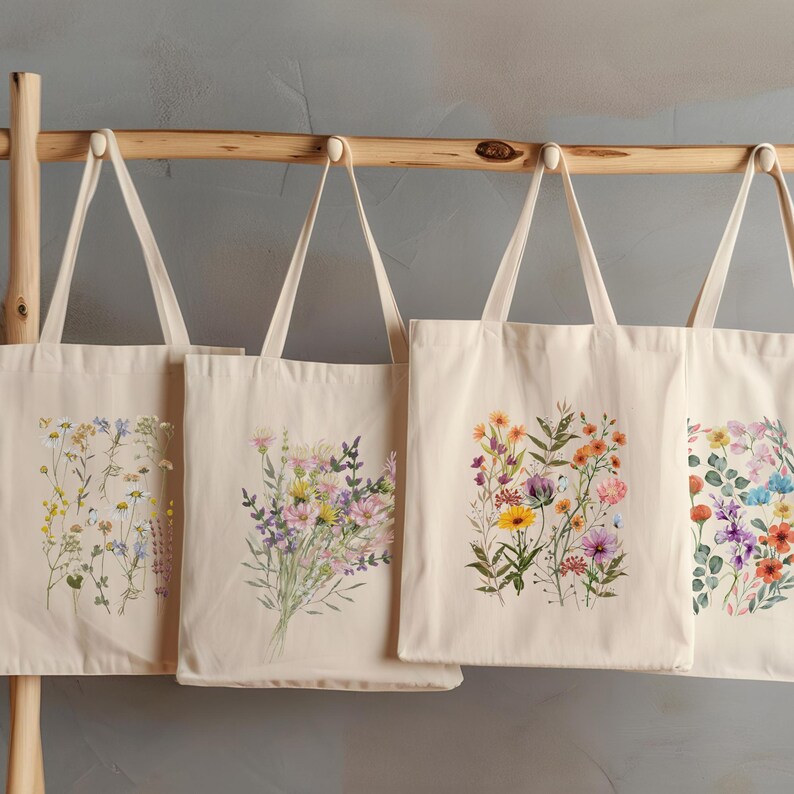 Op de afbeelding: Vier natuurlijke canvas tassen met verschillende bloemenontwerpen. Elke tas heeft een boeket kleurrijke wilde bloemen, waaronder roze, paarse, gele en oranje bloemen.