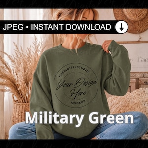 Puede incluir: Una sudadera verde militar con el texto "Your Design Here Mockup" en un diseño circular. Las palabras "Military Green" se muestran en letras blancas grandes en la parte inferior de la imagen. La imagen también incluye el texto "JPEG • INSTANT DOWNLOAD".