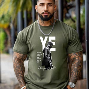 May include: Olive green t-shirt featuring the word "YE" in white block letters. Below the text is a black and white image of a person, with the text "TELLING TRUTH IS CRAZY IN A WORLD FULL OF LIES" and "Kanye West" in a script font.